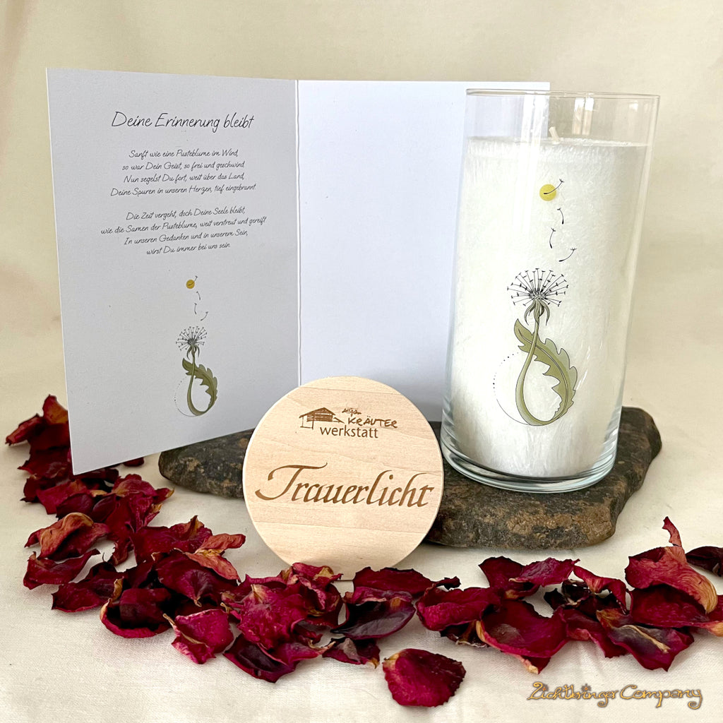 Trauerlicht Pusteblume aus der Allgäuer Heilkräutermanufaktur. Weiße Kerze im Glas, mit Beileidskarte, innen steht ein Gedicht.  Glas mit Aufdruck Pusteblume. Gravierter Holzdecke mit Aufschrift Trauerlicht.