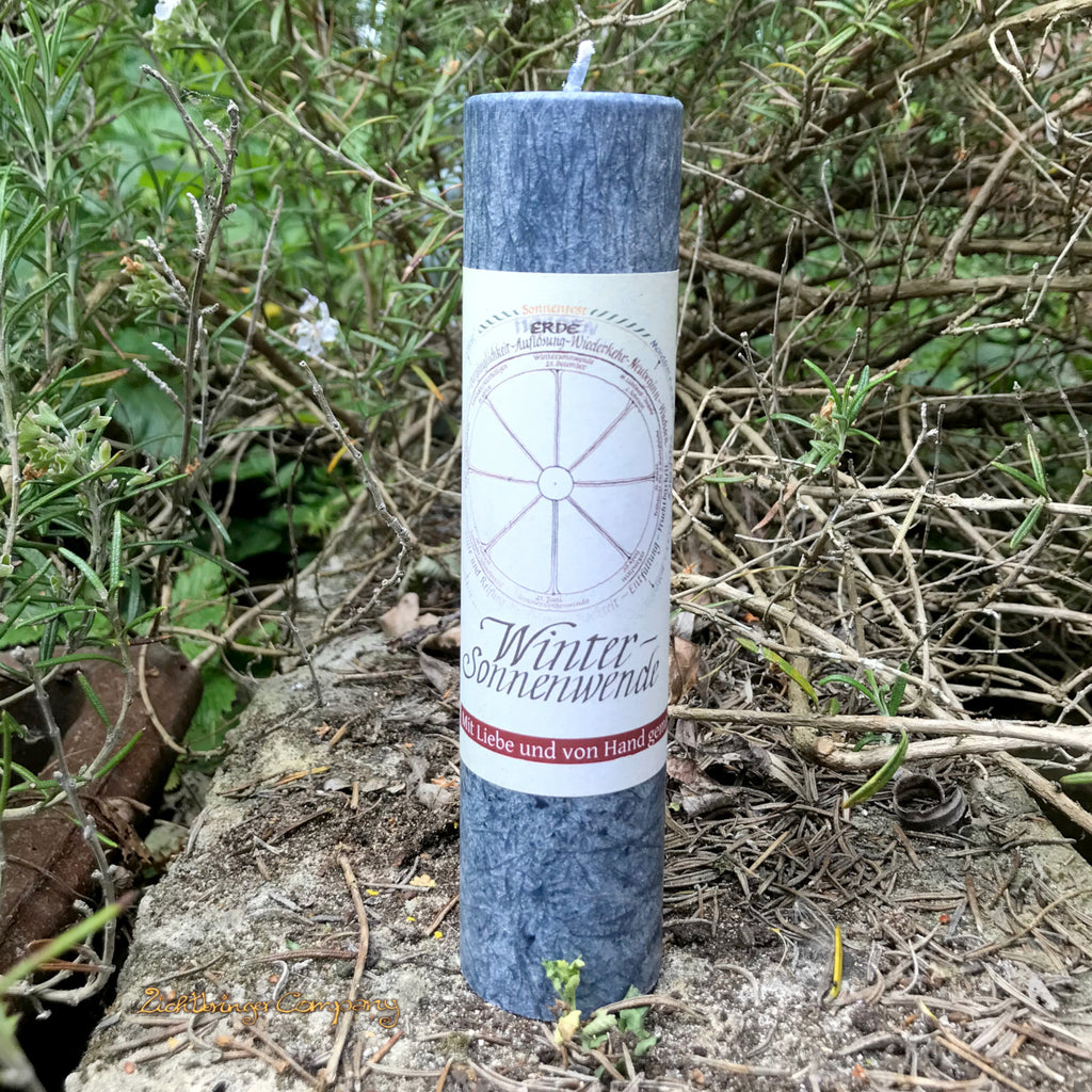 Wintersonnenwende Ritualkerze aus der Allgäuer Heilkräutermanufaktur. Farbe mitternachtsblau, auf einer Steinmauer