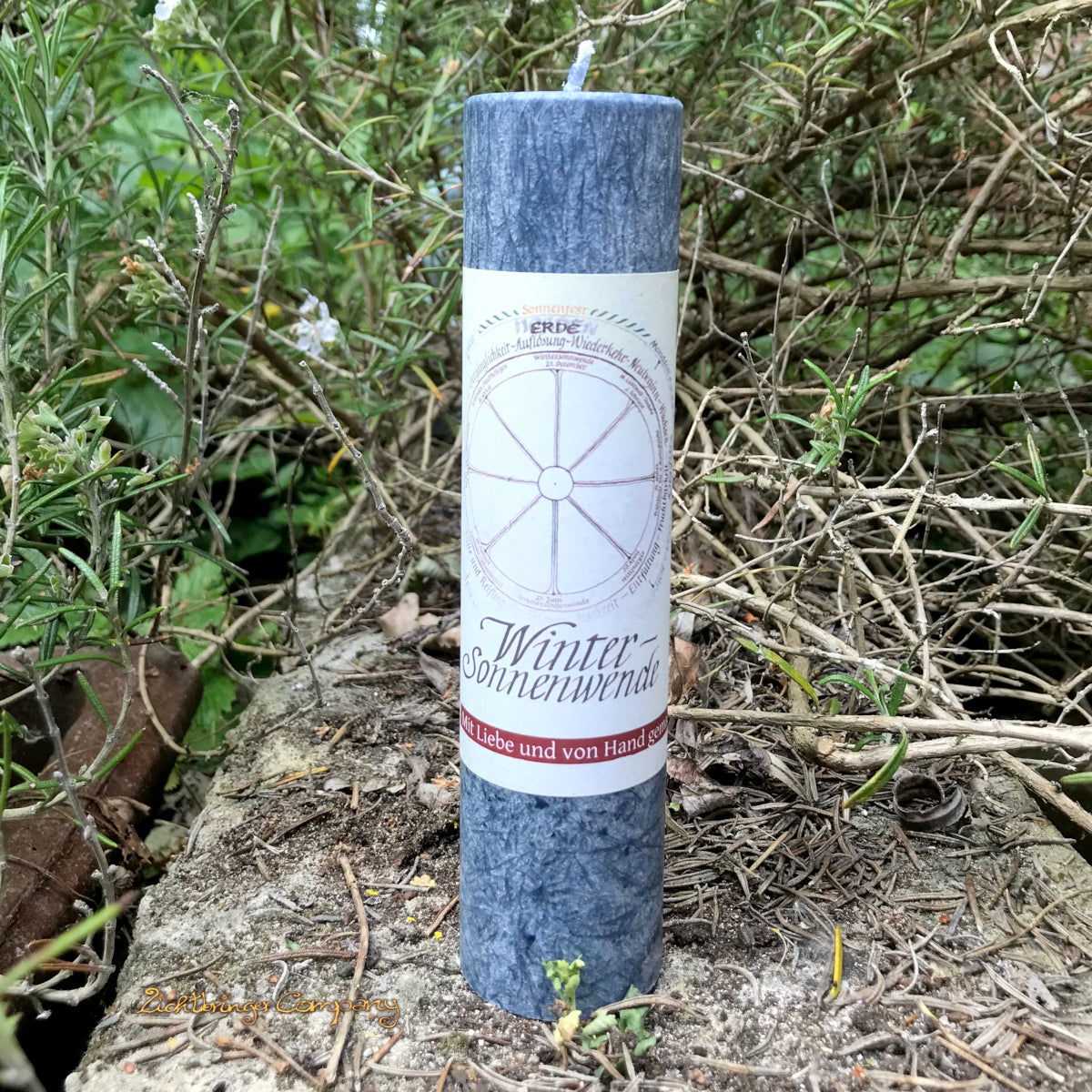 Wintersonnenwende Ritualkerze aus der Allgäuer Heilkräutermanufaktur. Farbe mitternachtsblau, auf einer Steinmauer