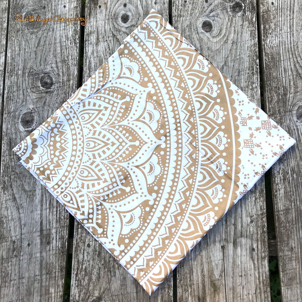 Detailaufnahme des goldenen Mandala-Musters auf weißem Tuch