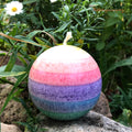 Regenbogenkerze in Kugelform, Farben von oben: gelb, orange, rot, lila, blau, grün. Jede Farbschicht ein anderer Duft.