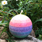 Regenbogenkerze in Kugelform, Farben von oben: gelb, orange, rot, lila, blau, grün. Jede Farbschicht ein anderer Duft.