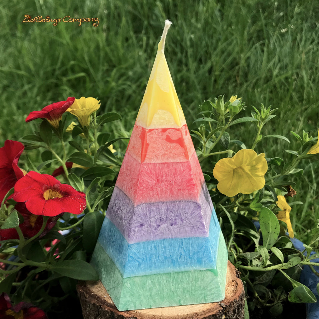 Regenbogenkerze in Pyramidenform, pro Farbschicht mit einem anderen Duft. Schichten, von oben: gelb, orange, rot, lila, blau, grün.